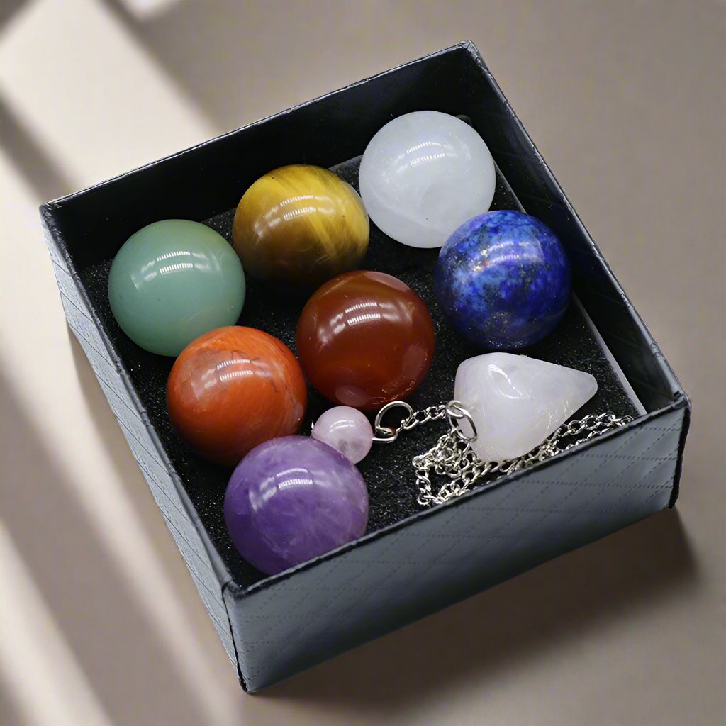 Chakra Gemstone Sphere Crystal Box Set with 7 chakra stones, rose quartz pendulum, and chakra balancing booklet.