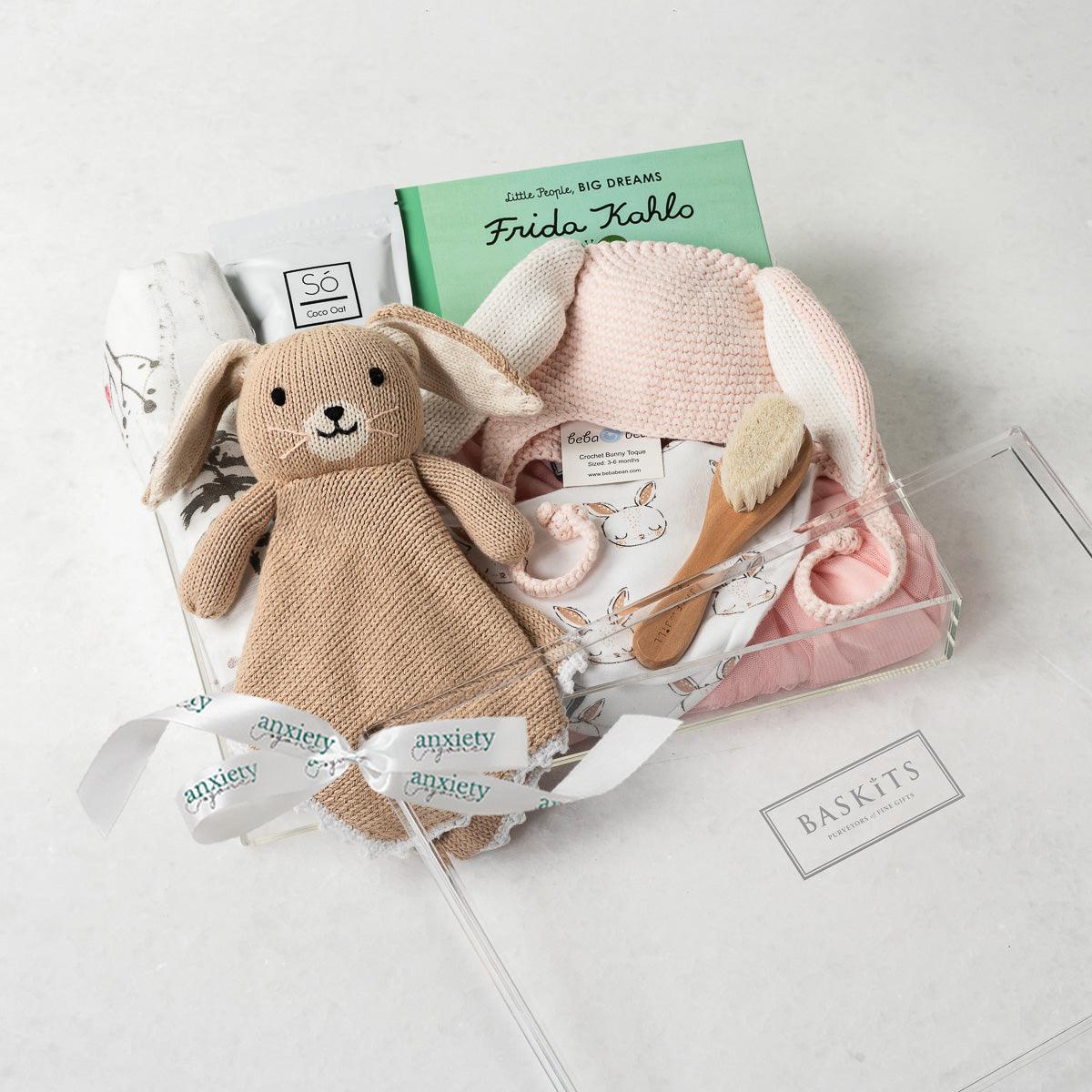 Little Bunny Gift Box – Unique baby gift basket with personalized baby gifts, including a pink tutu dress, gender-neutral baby items, custom newborn gifts, baby shower gift, baby girl gifts, forest-patterned swaddle, Bailey the Bunny Lovie, coconut &amp; oat milk bath, and Frida Kahlo book. Perfect new baby gift basket for welcoming a newborn with thoughtful and charming baby boy or girl gifts.