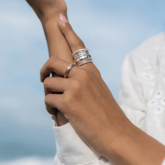 Sterling Silver Gold Fidget Ring with hammered spinning band, Rose Gold flower pattern, and Yellow Gold spinning band, displayed with complimentary MeditationRings Tin and Travel Pouch