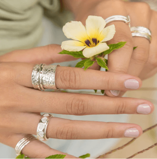 Karma Sterling Silver Spinner Ring with intricate floral detailing and two spinning bands, displayed with complimentary tin and travel pouch