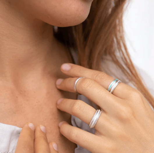 Sterling Silver worry ring with pearl white enamel design and CZ spinning band, displayed with complimentary MeditationRings Tin and Travel Pouch