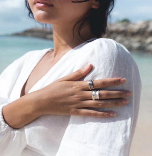 Devi Spinning Ring in luxurious sterling silver with flower-carved pattern and two spinning bands, displayed with complimentary tin