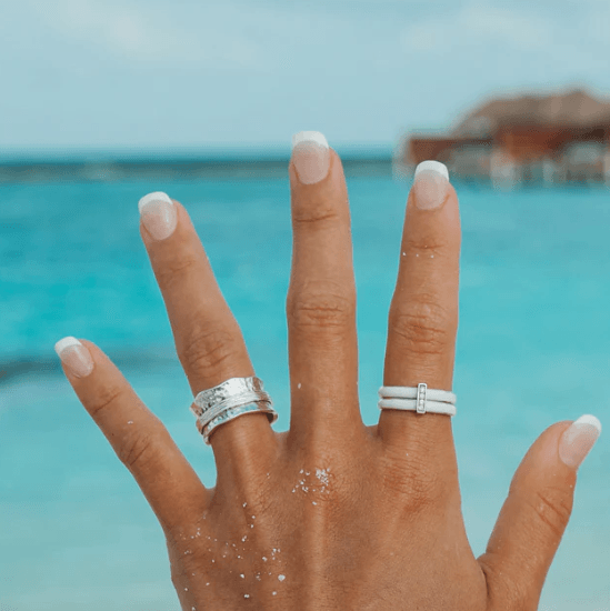 Sterling Silver Free-Floating Anxiety Ring with white enamel spinning bands and CZ accent bar, displayed with complimentary MeditationRings Tin and Travel Pouch