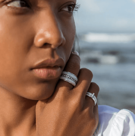 Sterling Silver Free-Floating Anxiety Ring with white enamel spinning bands and CZ accent bar, displayed with complimentary MeditationRings Tin and Travel Pouch