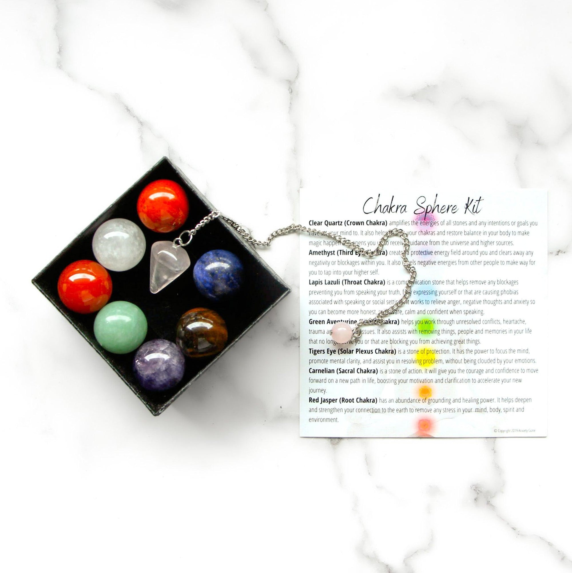 Chakra Gemstone Sphere Crystal Box Set with 7 chakra stones, rose quartz pendulum, and chakra balancing booklet.